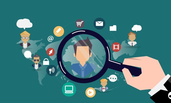 A magnifying glass focusing on a person's face, surrounded by various social media icons and a world map.