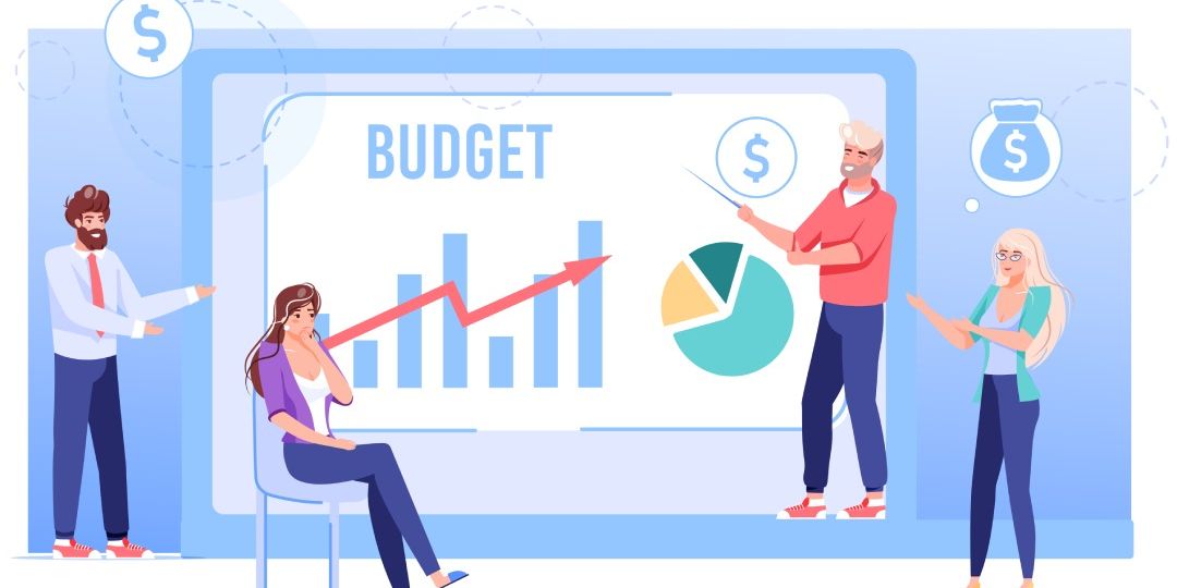 A group of people discussing a budget plan. They are standing around a large screen showing a bar graph, a pie chart, and the word "BUDGET."