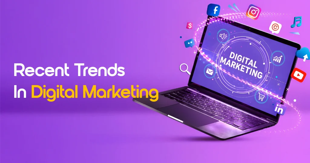 A laptop displaying the text 'DIGITAL MARKETING' on its screen, surrounded by floating icons for various social media and web platforms (like Facebook, Instagram, LinkedIn, YouTube). Text on the left reads: 'Recent Trends In Digital Marketing'.
